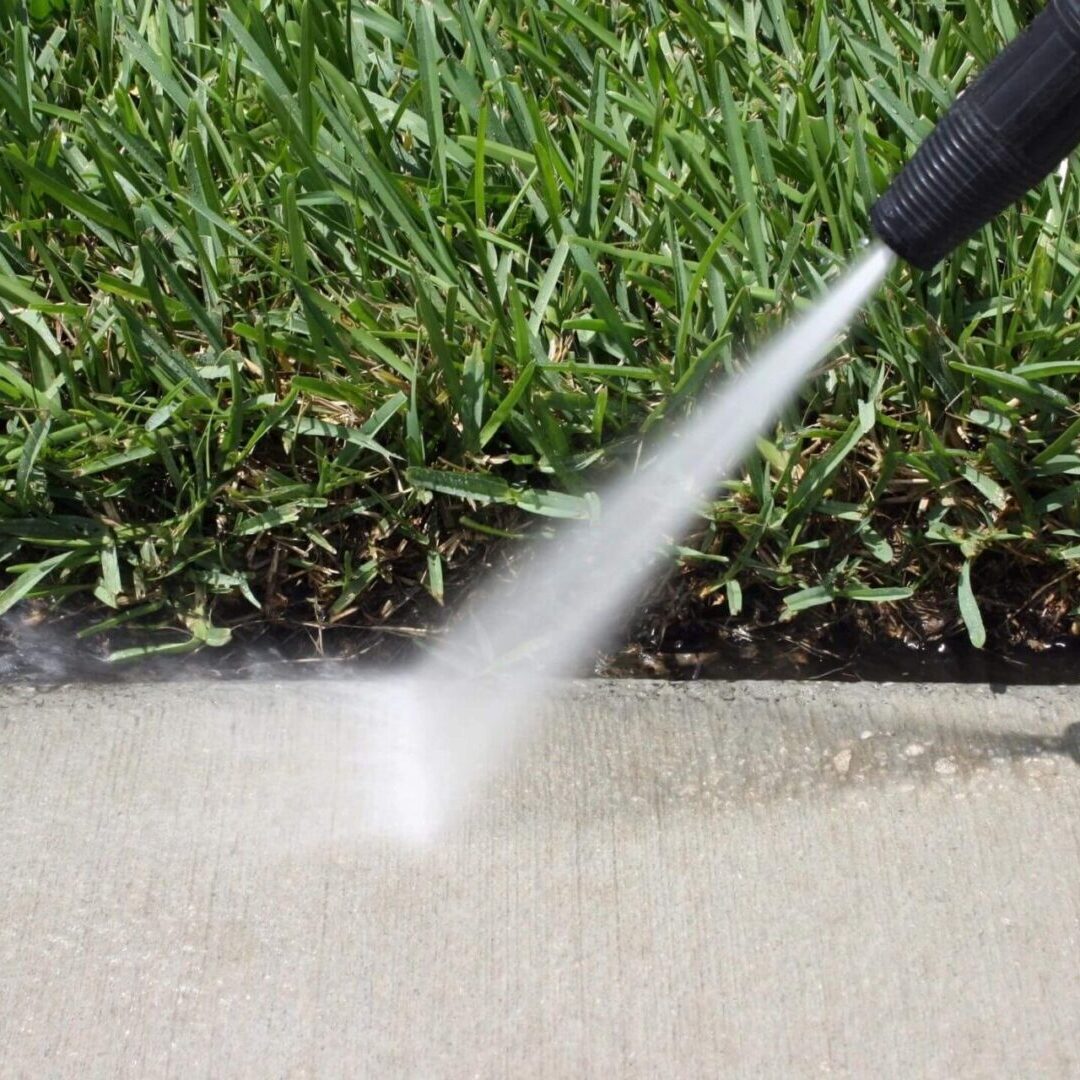 A person using a hose to clean the sidewalk.